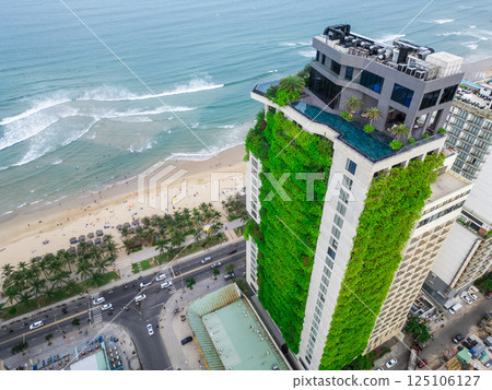eco friendly green building with vertical garden near ocean, city harmony concept, sustainable architecture and urban nature balance 125106127