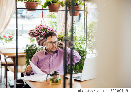 Man working on laptop online at table with food Man working on laptop online at table with food 125106149
