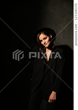 woman in black jacket and hat on dark background woman in black jacket and hat on dark background 125106370