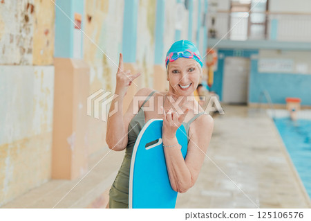 Senior, sport and portrait of swimmer with rock hand at retirement home pool with energetic smile. Wellness, happy and vitality of elderly woman excited for swimming fitness, exercise and fun. 125106576