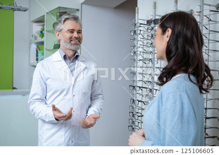 Woman choosing eyeglasses in optical store with oculist checking eyesight for vision care 125106605