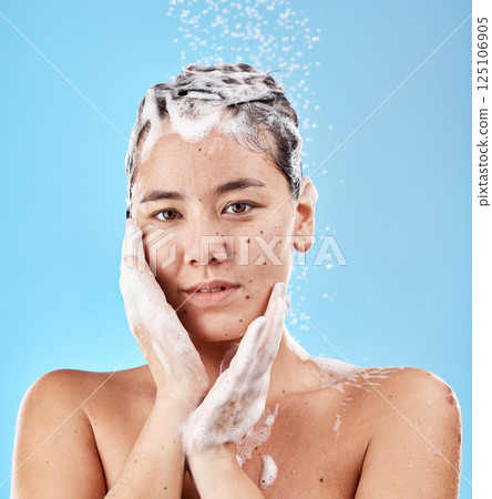 Shower, shampoo and hair care, woman with soap and clean portrait for grooming and hygiene against blue studio background. Face, hands and wellness with washing hair and beauty with water droplets. 125106905