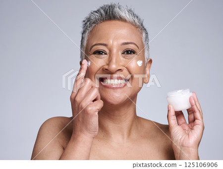 Cream, face and skincare senior woman in studio portrait for healthy glow, wellness and cosmetics promotion, advertising or marketing. Happy anti aging elderly model with skin care dermatology facial 125106906
