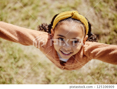 Top view, child or girl in fun game pov in nature park, garden environment or sustainability grass field in summer break. Portrait, smile or happy youth kid playing or jumping or in energy activity 125106909