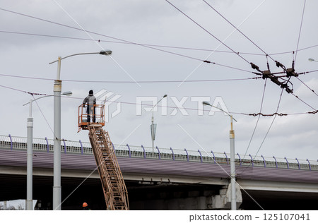Electrician works on tower above city's electrical networks. 125107041