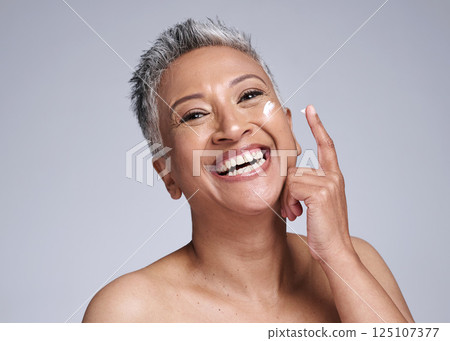 Skincare, cream or happy senior woman, healthy skin or smile for beauty product on face against grey studio background. Elderly latino model happiness, cosmetic wellness and sunscreen for body health 125107377