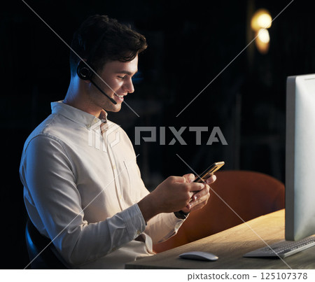 Man, headphones and smartphone in call center office at night for business communication online. Businessman, crm telemarketing and online customer service agent on company phone happy at work desk Man, headphones and smartphone in call center office at night for business communication online. Businessman, crm telemarketing and online customer service agent on company phone happy at work desk 125107378