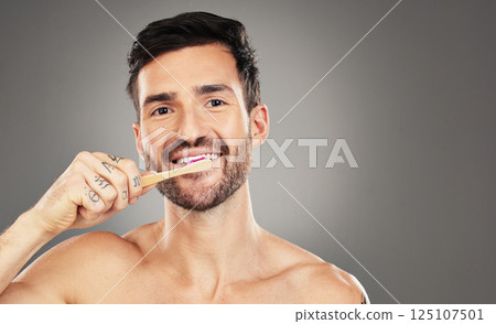 Brushing teeth, bamboo and man in studio for dental, dentist and mouth wellness with product promotion on mockup space. Model portrait with wood and eco friendly toothbrush for mint fresh breath Brushing teeth, bamboo and man in studio for dental, dentist and mouth wellness with product promotion on mockup space. Model portrait with wood and eco friendly toothbrush for mint fresh breath 125107501
