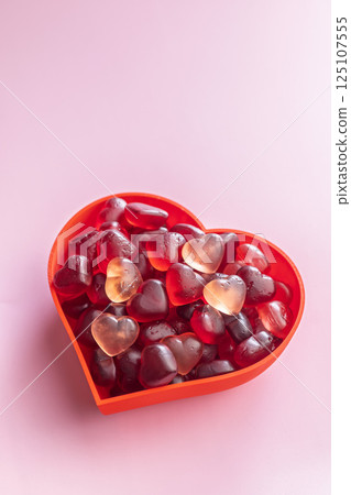 Heart shaped jelly candies in bowl on pink background. 125107555
