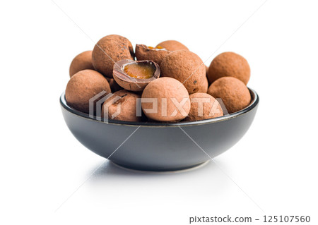 Chocolate truffles with cocoa powder and caramel filling in bowl isolated on white background. 125107560