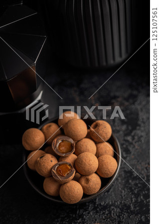 Chocolate truffles with cocoa powder and caramel filling on black table. 125107561
