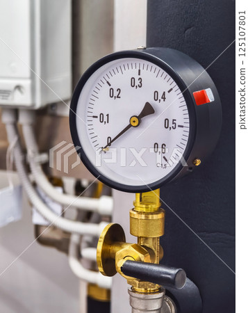Pressure gauge measuring fluid dynamics in industrial machinery at a manufacturing facility 125107801