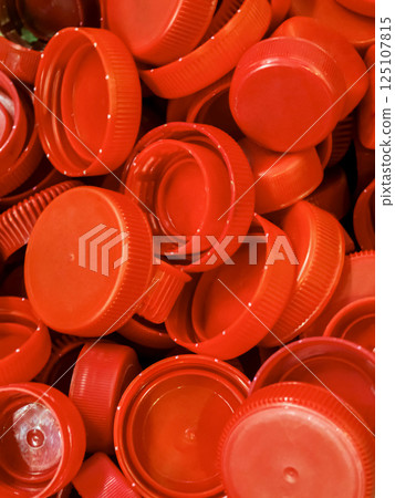 Bright red bottle caps collected in a pile showcasing recycling potential at a local facility Bright red bottle caps collected in a pile showcasing recycling potential at a local facility 125107815