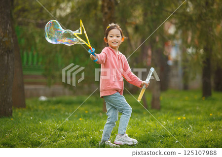 Happy Asian Girl Blowing Bubbles in Park on Sunny Day 125107988