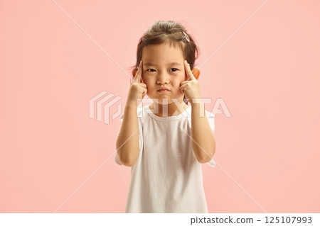 Pensive Child with Fingers on Temple trying remember something stands on pink isolated 125107993