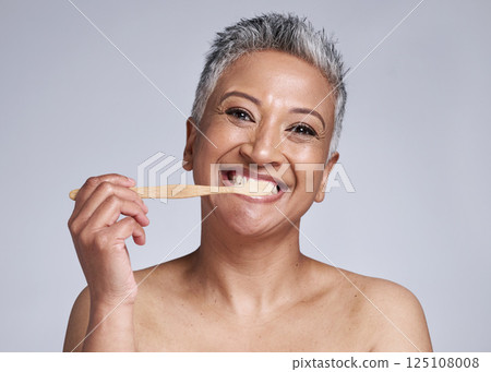 Mature woman, toothbrush and brushing teeth on studio background, morning grooming routine or healthcare wellness. Portrait, smile or beauty model in dental care cleaning or happy hygiene maintenance 125108008