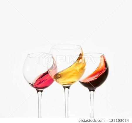 Rose, white, red wines splashes in stemware. 125108024