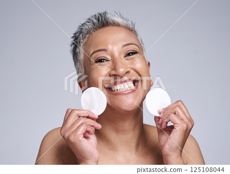Skincare, portrait and senior woman with cotton pad for natural, anti aging and beauty routine. Cosmetic, health and face of happy elderly lady with skin treatment isolated by gray studio background. Skincare, portrait and senior woman with cotton pad for natural, anti aging and beauty routine. Cosmetic, health and face of happy elderly lady with skin treatment isolated by gray studio background. 125108044