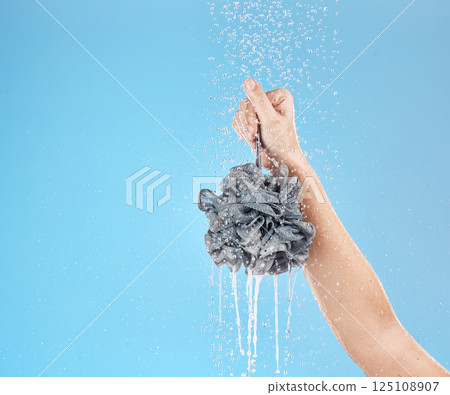 Shower, loofah and hand of woman in studio on blue background mock up. Skincare, water splash and female model holding sponge for showering, washing or bathing for hygiene, health or wellness mockup 125108907