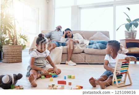 Tired parents on couch, children and playing with toys on weekend to relax, for bonding and sleepy in lounge. Family, mother and father with brother, sister and play educational games and exhausted. 125109016