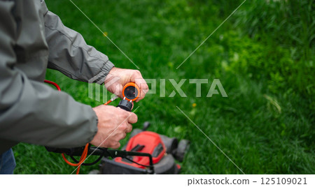 Maintenance of an electric lawn mower highlights the importance of garden care in springtime landscaping Maintenance of an electric lawn mower highlights the importance of garden care in springtime landscaping 125109021