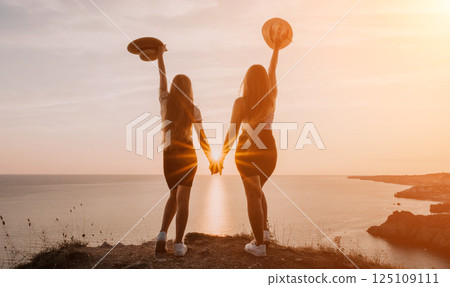 Two Women Silhouetted Against a Sunset Over the Ocean 125109111
