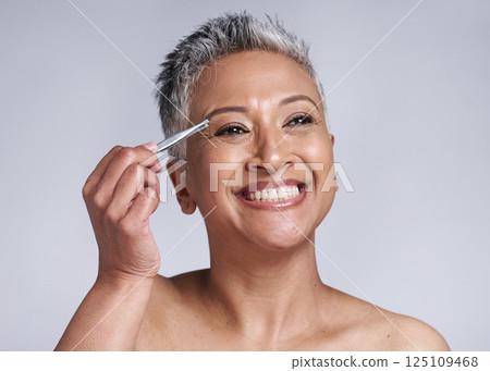 Beauty, eyebrow and hair removal of a senior woman in studio for skincare, cosmetics and makeup with a smile, happiness and glow. Mature model with tweezers for removing facial hair for clear skin 125109468