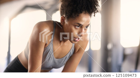 Gym, training and tired black woman breathing after exercise, workout and sports fitness. Woman in a health and wellness club breathe and relax after intense athlete challenge with focus 125109473