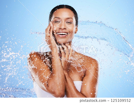 Water splash, woman and skincare for beauty, moisturizer or hydration by blue background wall. Black woman, skin model and splashes for cosmetics, health or dermatology wellness by cosmetic backdrop 125109552