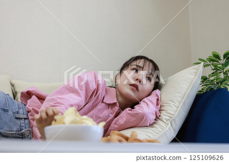 A woman eating sweets while watching TV A woman eating sweets while watching TV 125109626