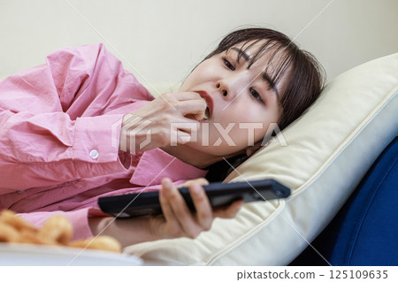 吃甜點的婦女，當看電視時 125109635