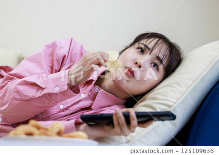 吃甜點的婦女，當看電視時 125109636