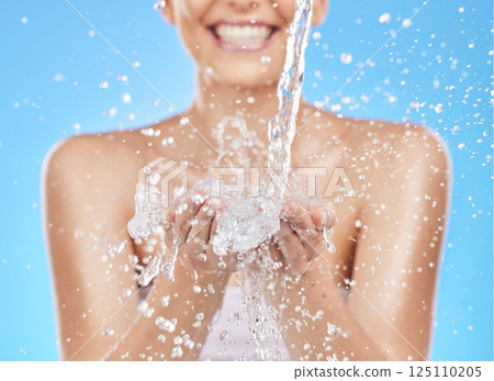 Skincare, hands and woman with splash of water for cleaning, washing and facial cleanse. Wellness, hydration and girl with liquid stream for luxury spa, beauty and hygiene in blue background studio 125110205