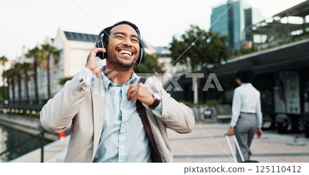 Business, man and laughing outdoor with headphones for morning commute, comedy podcast or streaming radio. Professional, person and happy in city for job opportunity, sound track and walking to work 125110412