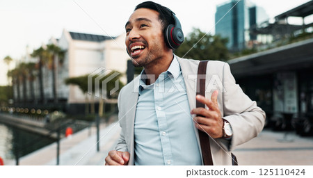 Businessman, happy and dancing outdoor with headphones for morning commute, audio playlist or streaming music. Professional, person and walking in city with sound track, radio and travel to new job 125110424
