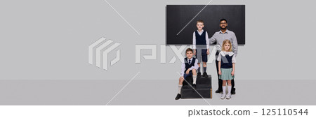 Smiling teacher standing proudly with three students in school uniforms in front of chalkboard. 125110544