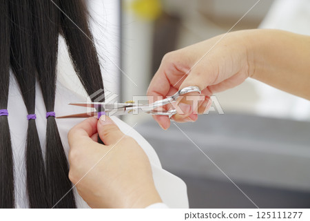 A woman cutting hair for hair donation 125111277