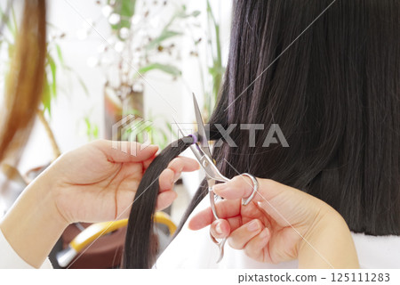 A woman cutting hair for hair donation 125111283