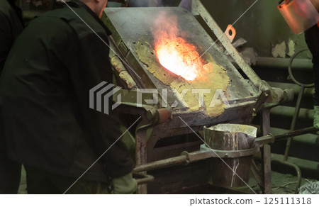 Workers at metallurgical plant pour molten metal from furnace into foundry ladle Workers at metallurgical plant pour molten metal from furnace into foundry ladle 125111318