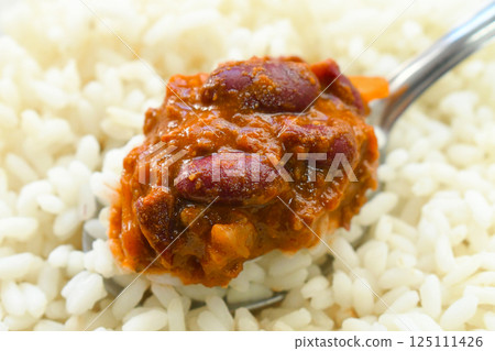 Chilli con carne with rice on spoon. Traditional Mexican food. Chilli con carne with rice on spoon. Traditional Mexican food. 125111426