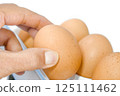 Hand pick chicken egg from the refrigerator tray. 125111462