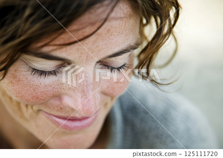 A potrait of middle aged woman looking naturally, wreckles on face 125111720