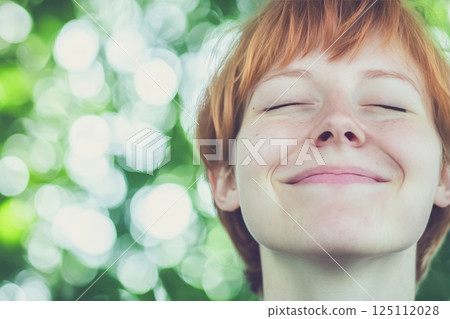 A beautiful woman with shiny face with few wreckles, smiling, eyes closed, enjoying life 125112028