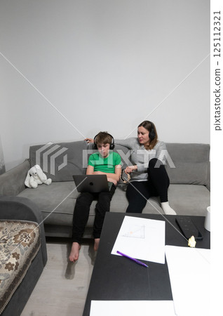 Engaging home study session for child with mom providing guidance on a cozy sofa during late afternoon at a modern living room Engaging home study session for child with mom providing guidance on a cozy sofa during late afternoon at a modern living room 125112321