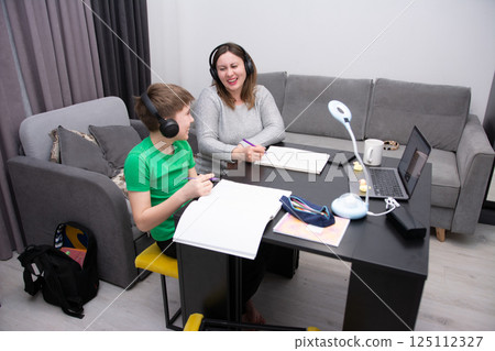 Engaging learning experience between a mother and son at home during a cozy afternoon with creative activities and technology Engaging learning experience between a mother and son at home during a cozy afternoon with creative activities and technology 125112327