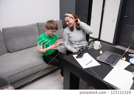 Joyful moments of a mother and son sharing laughter over video games at home in a cozy living room filled with warmth and connection during a weekday evening Joyful moments of a mother and son sharing laughter over video games at home in a cozy living room filled with warmth and connection during a weekday evening 125112329