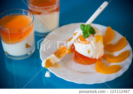 Bright jelly with pieces of peaches and milk jelly on a blue background 125112467