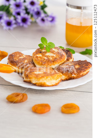 Homemade cheese pancakes with a delicate texture and aromatic dried apricots Homemade cheese pancakes with a delicate texture and aromatic dried apricots 125112473
