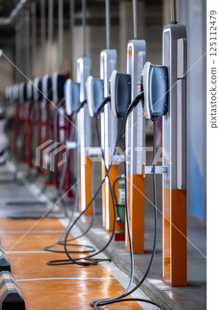 EV charging station and electric car, Electric car charging station for charge EV battery, Plug for vehicle with electric engine, EV charger clean energy, Charging point at car parking lot. 125112479