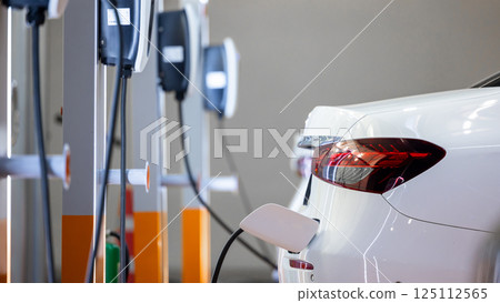 EV charging station and electric car, Electric car charging station for charge EV battery, Plug for vehicle with electric engine, EV charger clean energy, Charging point at car parking lot. 125112565
